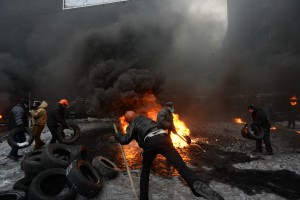 Protesters throwing tires to the fire set by the protesters to p
